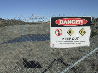 An abandoned mine area became a pool as the time pass by, chain link fence with warning board beside the abandoned area to warn people should not enter.