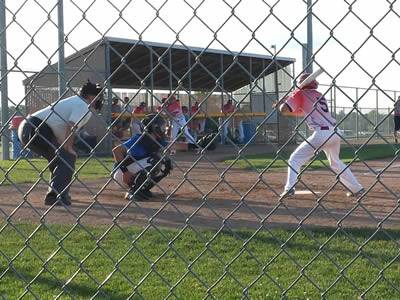 People playing baseball game behind the chain link fence.