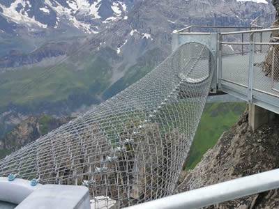 Cylindrical chain link thrill walk is on the halfway of the cliff.