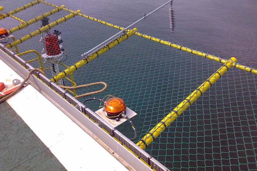 Green chain link safety panel of helicopter pad on the sea.