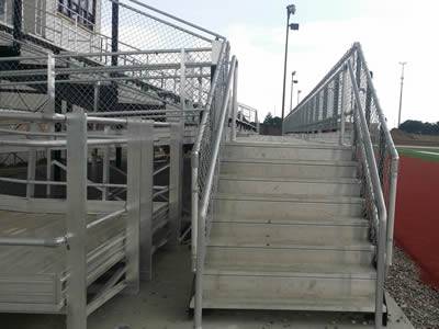 Sports equipment storage house in the high school playground, its stair surrounded by chain link fence.