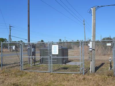 Framed chain link portable security fencing around substation near a road.