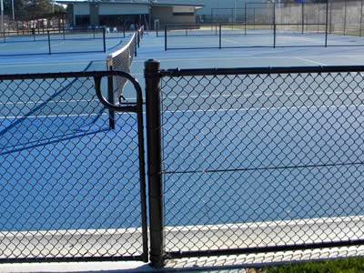 Tennis court is surrounded by chain link fence with a chain link mesh gate.
