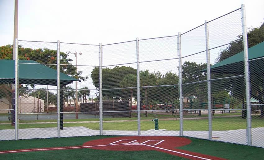 Chain link fence is quite tall baseball backstop fence in the commercial area.
