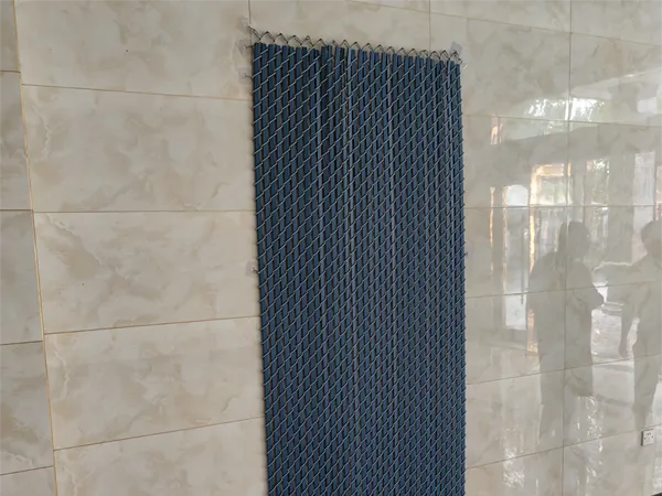 Blue chain link fence slats are hanging on a wall for display.