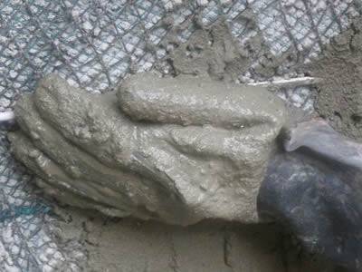 Applying concrete mud to the plaster mesh wall.