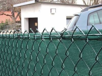Chain link windbreak fencing around the courtyard consists of chain link fence and dark green woven fabric.