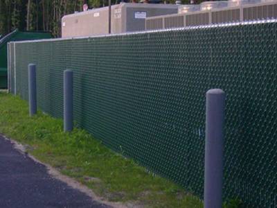 Green chain link fence privacy slats for residential fence along a busy road.