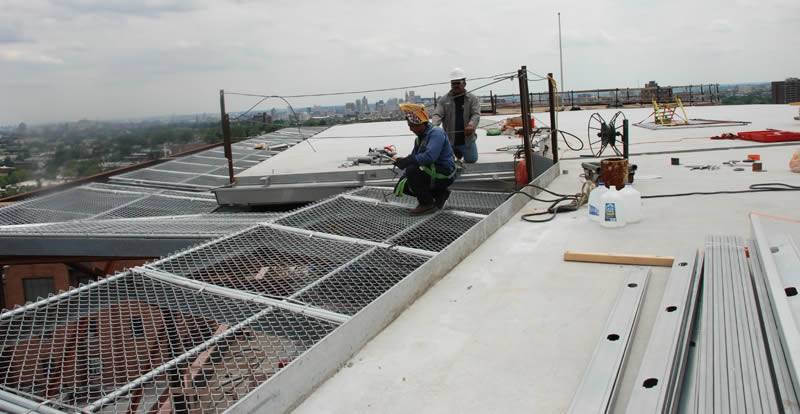 Workers are installing chain link safety panels for helicopter roof.