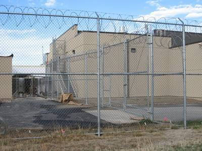 High security chain link fence with barbed wire and razor wire above.