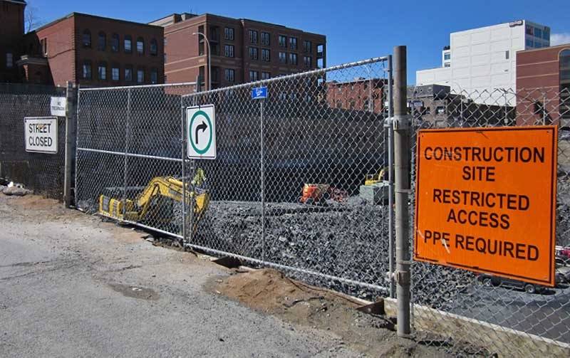 Temporary chain link fence around debris, and hanging warning signs for warning.