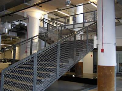 Indoor stair handrail with framed chain link fence for security protection.