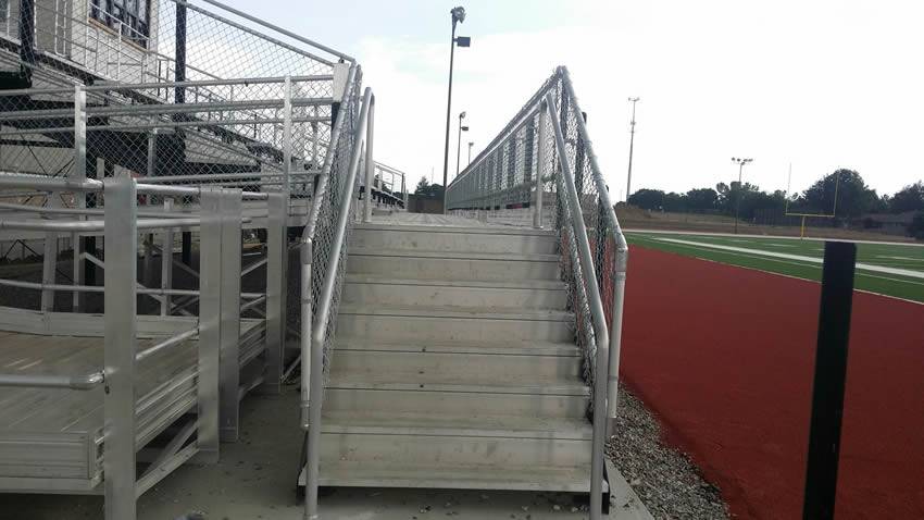 Sports equipment storage house in the high school playground, its stair surrounded by chain link fence.