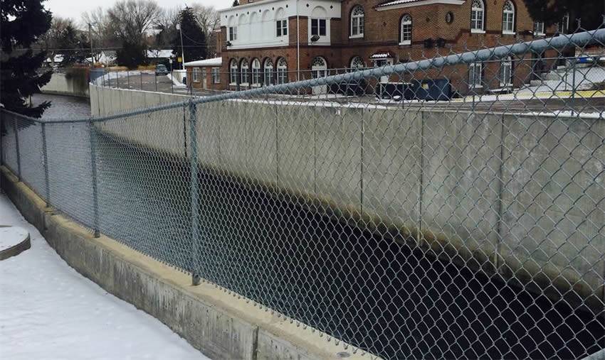 A river channel with chain link security fence, in front of a department.