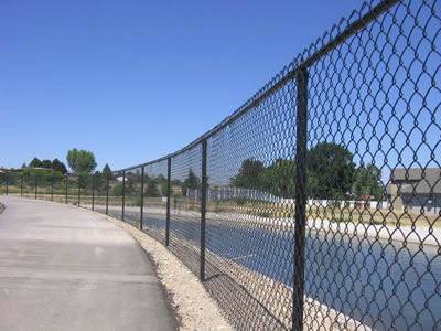 An artificial river with chain link security near a pedestrian walkway.