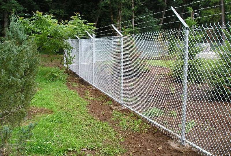 Security chain link fence with three strands of barbed wire to prevent turning.