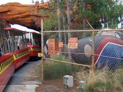 Chain link fence is the border separating train and grove.
