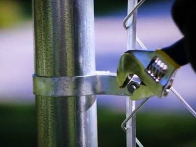 A man is tightening carriage bolts to secure tension bar.